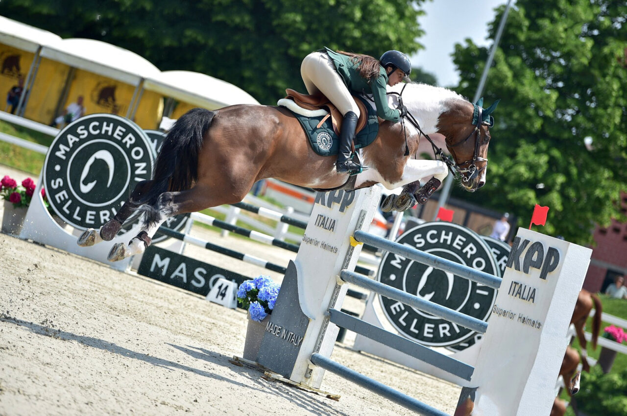 Michol mentre affronta un salto con il suo cavallo pezzato